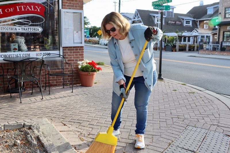Lewes Mayor Amy Marasco sweeps up debris on Second Street. Marasco said Community Service Day is a great opportunity to bring together city staff, Board of Public Works employees and volunteers.